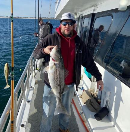 Man holding Striped Bass on a boat