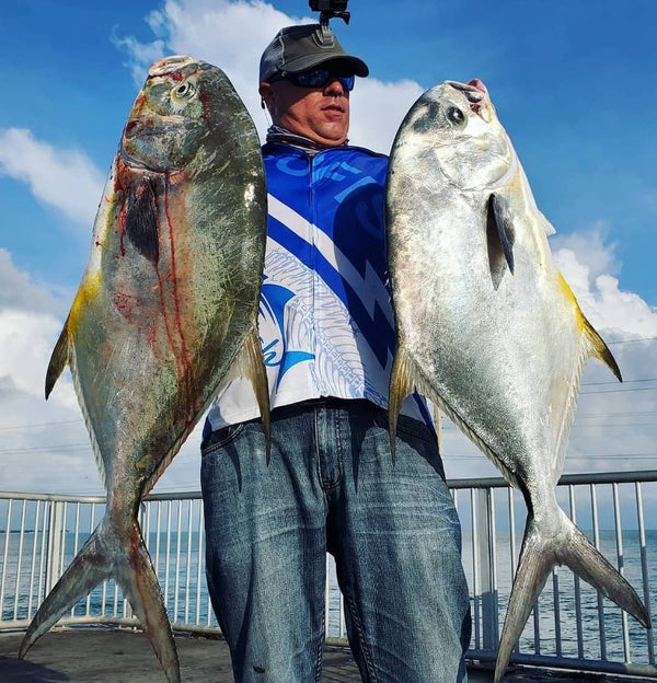 Man Holding 2 fish on a bridge