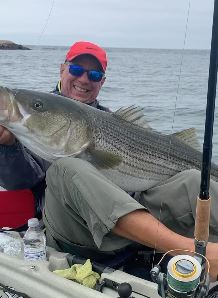 Man on kayak holding a striped bass fish