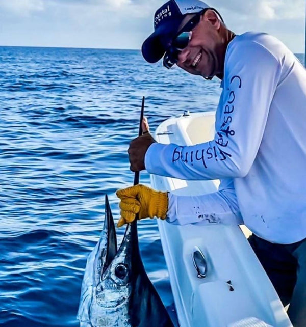 Man holding sailfish off the side of a boat