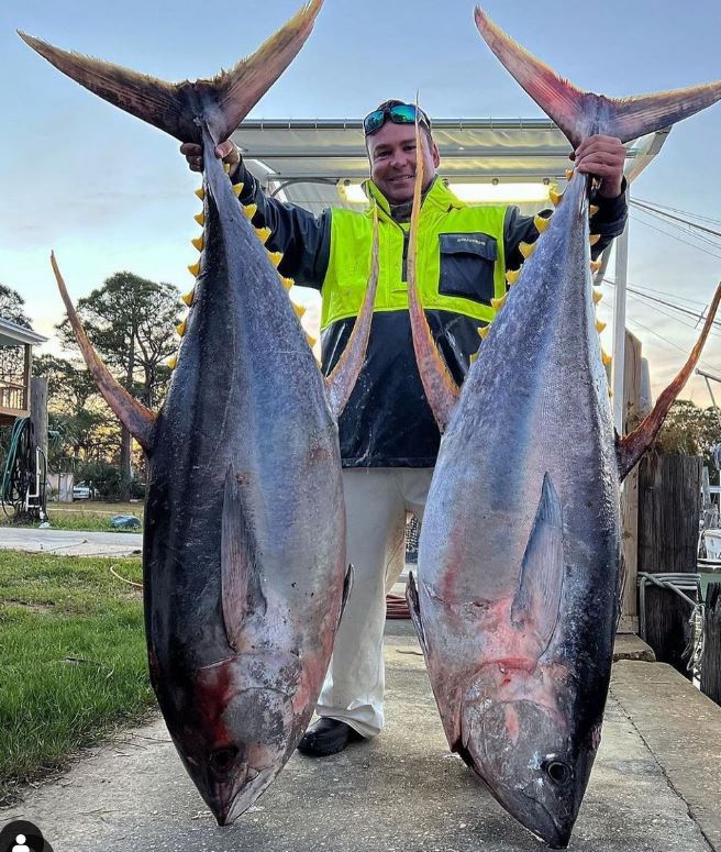 Man holding 2 giant tunas